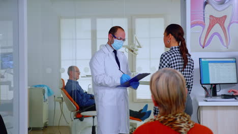 Dentist-doctor-interrogating-woman-taking-notes-on-clipboard