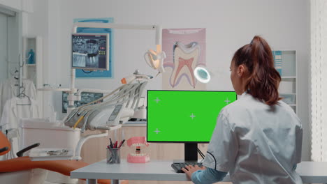 Dentist-using-computer-with-horizontal-green-screen-on-display