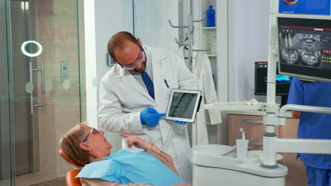 Dentist-in-dental-office-examining-x-ray-image-on-tablet