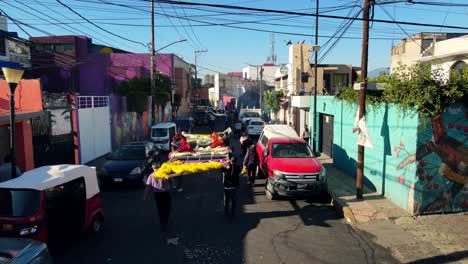 Bird's-eye-view-establishing-a-parade-of-people-carrying-giant-flower-decorations-in-commemoration-of-the-Day-of-the-Dead-in-Iztapalapa,-Mexico-City