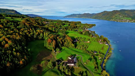 Farms-and-fields-along-the-shore-of-Attersee-Lake,-Austria---pullback-aerial