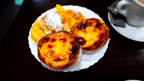 Happy-woman-having-breakfast-with-coffee-and-traditional-Portuguese-pastries