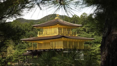 The-golden-pavilion-building,-exterior-shot-in-kyoto,-surrounded-by-forest-mountains