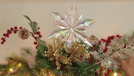 Placing-silver-sprig-on-decorated-top-of-christmas-tree-with-star