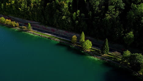 A-two-lane-road-along-the-banks-of-Attersee-Lake,-Austria---aerial-reveal