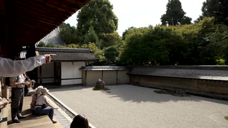 Guide-Pointing-Out-The-15-Stones-That-Can-Be-Viewed-At-The-Zen-Rock-Garden-At-Ryoanji-Temple