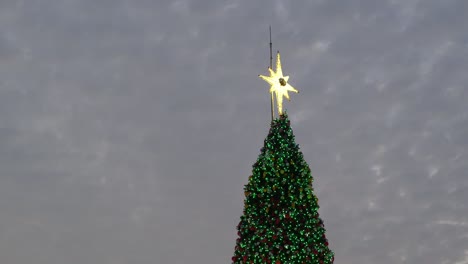 Der-Stern-Sitzt-Hoch-Oben-Auf-Dem-Weihnachtsbaum,-Der-Mit-Hellen-Blinkenden-Lichtern-Geschmückt-Ist