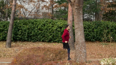 Side-View-of-Middle-Age-Fit-Man-Running-in-a-Park-Around-Modern-Apartment-in-Autumn