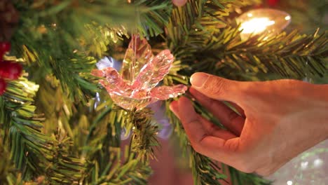 Anbringen-Eines-Kolibri-Ornaments-Aus-Rosafarbenem-Kristall-Auf-Einem-Geschmückten-Weihnachtsbaum
