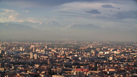 Massive-Alps-and-Milan-city-bellow-during-sunset,-aerial-view