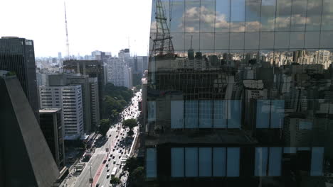Aerial-footage-revealing-the-main-boulevard-in-Sao-Paulo-from-behind-a-reflective-skyscraper