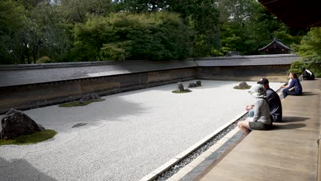 Tourists-Sitting-On-Veranda-Admiring-Ryoanji-Temples-Zen-Rock-Garden-In-The-Morning