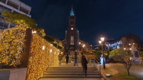 Gente-Caminando-Por-Las-Escaleras-De-La-Catedral-De-Myeongdong-Por-La-Noche-Tomando-Fotografías-Con-Decoraciones-De-Guirnaldas-Brillantes---Lapso-De-Tiempo-En-Seúl,-Corea-Del-Sur