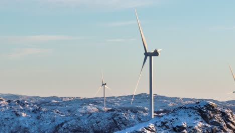 Luftaufnahme-Von-Windkraftanlagen-Auf-Schneebedeckten-Berghügeln-An-Sonnigen-Wintertagen,-Drohnenaufnahme