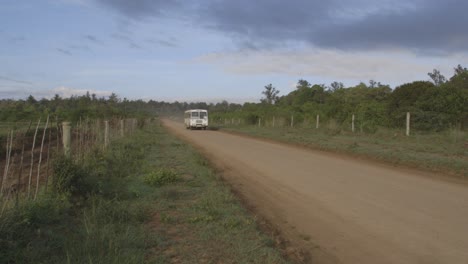 Weißer-Bus,-Der-Auf-Einer-Unbefestigten,-Leeren-Straße-In-Afrika,-Kenia,-Vorbeifährt