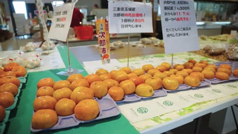 Close-pan-over-Persimmons,-Japanese-"Kaki"-at-Market