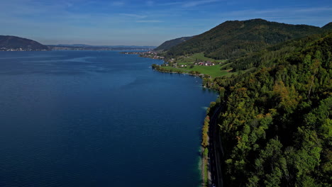 Attersee-Lake-in-Austria-with-a-picturesque-village-by-the-forest---aerial-view