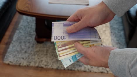 Man-Engages-with-Norwegian-Currency,-holding-many-banknotes-in-the-hand