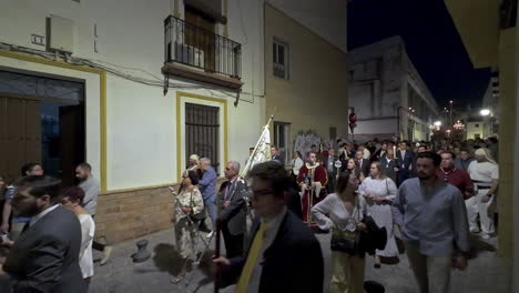 Religiöse-Menschen,-Die-Während-Der-Karwoche-Nachts-An-Der-Prozession-Auf-Der-Straße-Von-Sevilla-In-Spanien-Teilnehmen