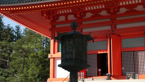 Linterna-Ornamentada-Con-Vista-Parcial-De-La-Pagoda-Konpon-Daito-De-Color-Rojo-Brillante-Al-Fondo-En-Koyasan
