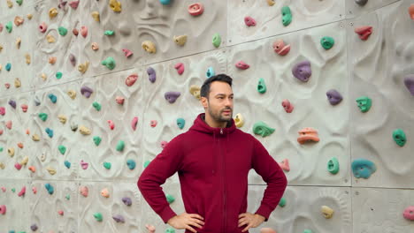 Man-Climber-Heavily-Breathing-After-Exercising-on-Climbing-Wall-at-Outdoor-Sport-Ground,-Hands-on-Waist-Pose