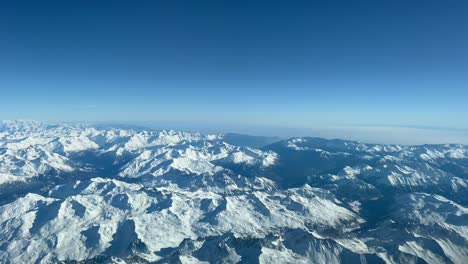 Alpine-snowy-landscape-shot-from-an-airplane,-as-seen-by-the-pilots-while-flying-at-8000m-high-in-a-spectacular-winter-day