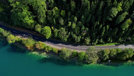 A-road-winds-along-the-banks-of-Attersee-Lake,-Austria---aerial