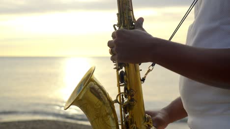 Langsam-Absteigende-Aufnahme-Eines-Saxophonisten,-Der-Bei-Sonnenuntergang-Am-Strand-Musik-Spielt