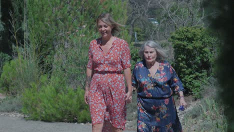Slow-motion-shot-of-a-senior-mother-and-daughter-walking-together-in-a-garden
