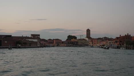 Murano-township-after-sunset-from-moving-boat,-handheld-view