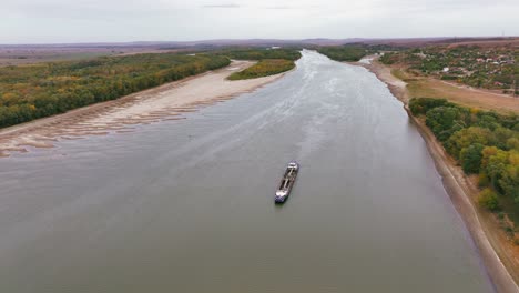 Aerial-shot-of-a-dredger-that-glides-through-a-big-river,-reshaping-the-landscape