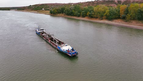 Aerial-shot-of-a-dredger-that-glides-through-a-big-river,-reshaping-the-landscape