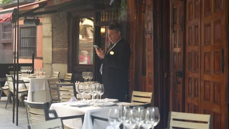 Restaurant-manager-speaks-with-phone-by-standing-outside