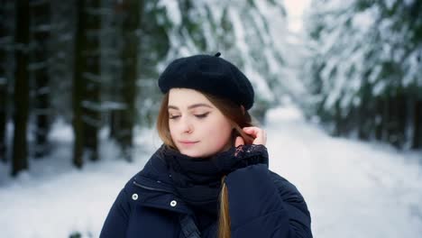 Close-up-shot-of-young-caucasian-female-fixing-her-hair-while-looking-at-the-snow-covered-forest-floor-at-daytime