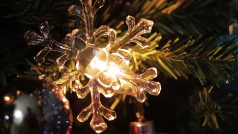 Light-shining-through-crystal-snowflake-decoration-on-christmas-tree