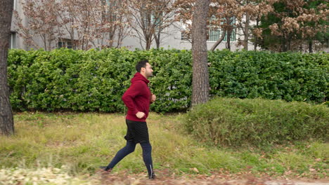 Profile-of-Sporty-Man-in-30s-Jogging-in-a-Park-in-Autumn---tracking-motion