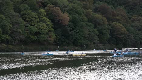 Tourists-Seen-Rowing-Small-Blue-Boats-On-Katsura-River-In-Arashiyama-Kyoto