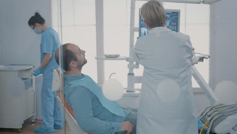 Sanitäter-Zeigt-Auf-Röntgenscan-Diagnose-Auf-Monitor-Im-Zahnarztschrank