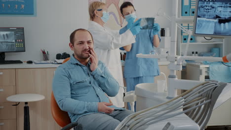 Zahnmedizinischer-Patient-äußert-Schwere-Zahnschmerzen-Im-Mundpflegeschrank