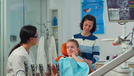 Child-using-finger-to-point-affected-tooth-while-the-dentist-talking-with-mother