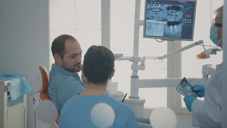 Zahnarzt-Und-Krankenschwester-Erklären-Einem-Patienten-Mit-Zahnschmerzen-Den-Röntgenscan