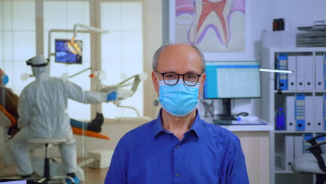 Portrait-of-elderly-man-with-mask-in-dental-office-looking-on-camera