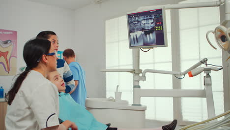 Kinderzahnarzt-Zeigt-Auf-Dem-Monitor-Ein-Röntgenbild-Der-Zähne