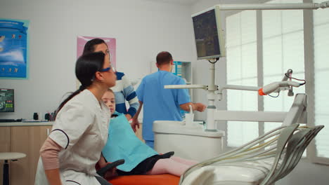 Der-Stomatologe-Zeigt-Auf-Den-Digitalen-Bildschirm-Und-Erklärt-Der-Mutter-Das-Röntgenbild