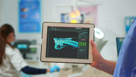Close-up-dentist-assistant-holding-tablet-with-digital-dental-fingerprint