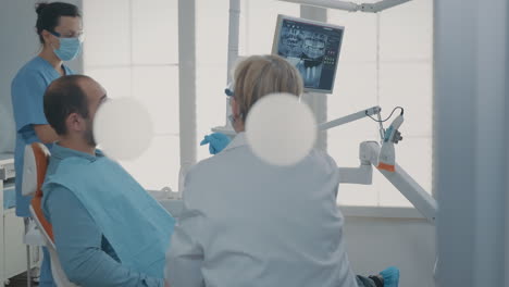 Zahnarzt-Zeigt-Auf-Die-Röntgenaufnahme-Der-Prothese-Auf-Einem-Digitalen-Tablet