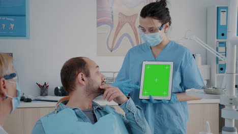 Assistant-vertically-holding-digital-tablet-with-green-screen