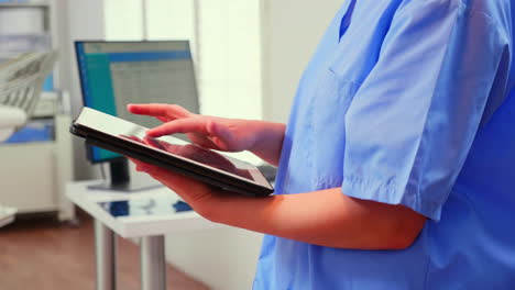 Close-up-of-assistant-holding-tablet-and-analysing-teeth-x-ray