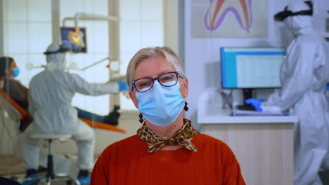 Portrait-of-retired-patient-with-mask-in-dental-office-looking-on-camera