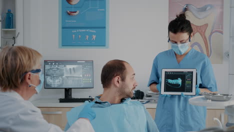 Equipo-Estomatológico-Apuntando-A-La-Radiografía-De-La-Prótesis-Dental-En-La-Tableta